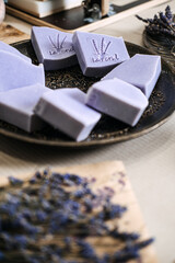 Close-up of handmade lavender soap bars with engraved design on tray. Natural skincare, artisan soap, organic beauty, sustainable living, eco-friendly concept