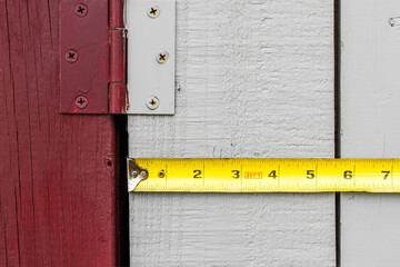 Holding a measuring tape across a wood shed's door