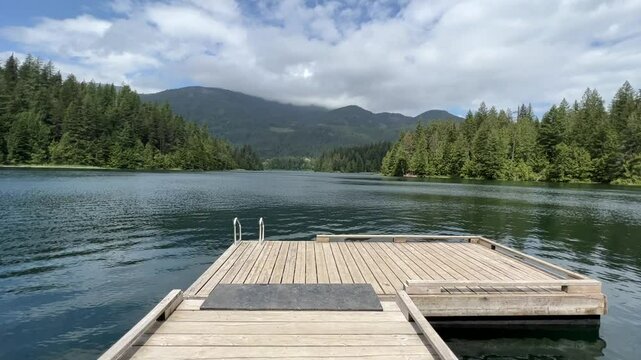 Weaver lake pier in British Columbia, Tranquil lake scene with wooden dock, diving board, and lush forest backdrop. Perfect for relaxation.