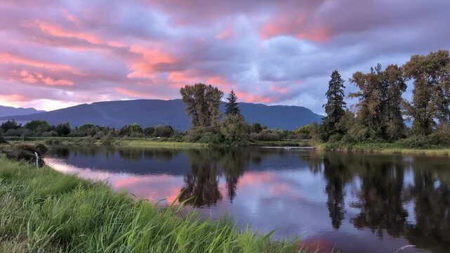 A stunning sunset paints the sky over the Alouette River in Pitt Meadows, BC. The vibrant colors reflect on the calm water, creating a peaceful and picturesque scene.