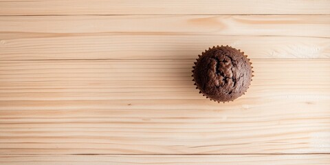 Top-Down View of a Perfectly Baked Chocolate Muffin on a Rustic Wooden Table