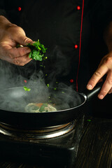 Fototapeta premium A cook adds chopped greens to a frying pan with eggs by hand. Concept of making fried egg for breakfast.