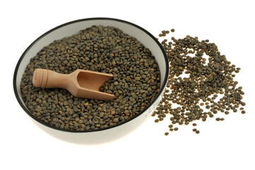 Assiette de lentilles du Puy sèches avec une cuillère en bois vue de dessus en gros plan sur fond blanc