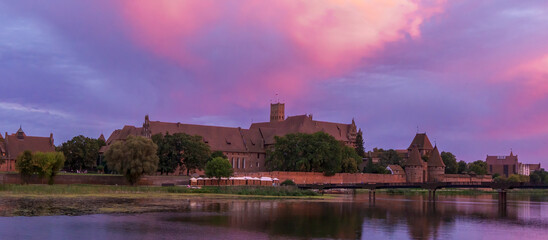 The Teutonic Castle in Malbork on the Nogat River during sunset