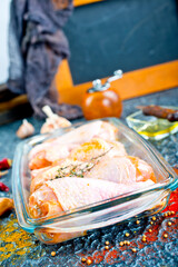 Raw chicken drumsticks with seasonings in glass plate. Chicken legs ready to cook.