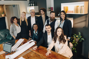 Team of architects and engineers gathering around table smiling at the camera