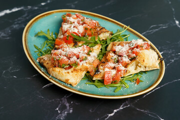 Slices of bruschetta with tomato, salad and parmesan cheese