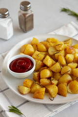 Homemade Oven Roasted Potatoes with Ketchup on a Plate, side view.