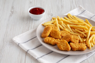 Fried Chicken Nuggets with French Fries on a Plate, side view. Copy space.
