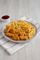 Fried Chicken Nuggets with French Fries on a Plate, side view.