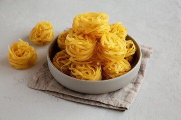 Raw Dry Tagliatelle Pasta in a Bowl, side view.