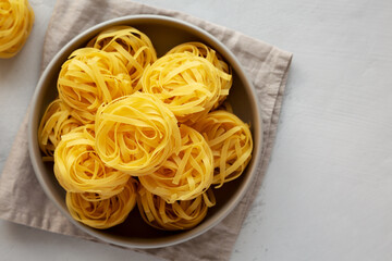 Raw Dry Tagliatelle Pasta in a Bowl, top view. Flat lay, overhead, from above. Copy space.