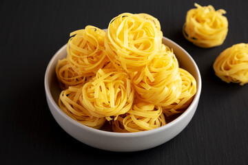 Raw Dry Tagliatelle Pasta in a Bowl, side view.