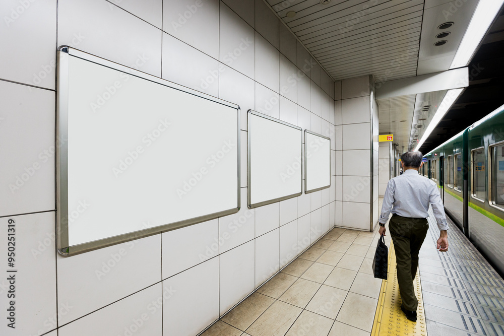 Wall mural an executive japanese man with a suitcase walks past three blank billboard advertising posters on a 