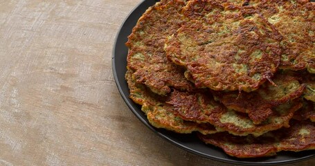 Close up view of zucchini and chickpea flour pancakes on a plate. Vegan snack or lunch. Copy space. Table spin.