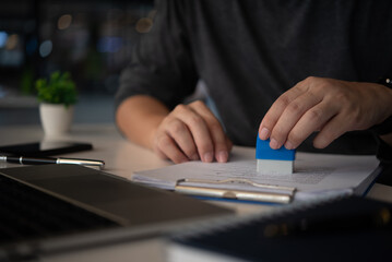 person stamping documents in an office setting, representing document processing, official...