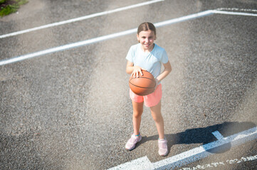 girl child in sportswear playing basketball game