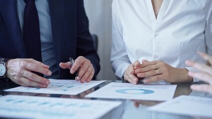 Business people wearing suits are reviewing a financial results and discussing the terms of the agreement. Teamwork and planning