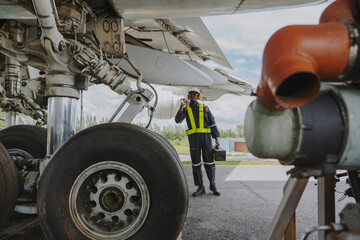 Mechanics inspect the engines of a large plane before takeoff at a summer airport.
