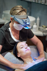 Woman, therapist or light with body treatment in exfoliation or collagen at indoor salon. Female...