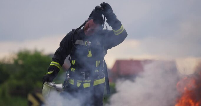 Portrait of a heroic fireman in a protective suit. Firefighter in fire fighting or car accident rescue operation in dusk or night.