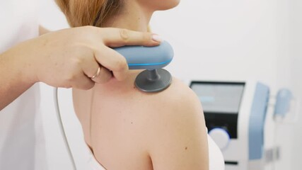 A professional physiotherapist administers electromagnetic therapy to a young woman in a state-of-the-art clinic. This advanced treatment aids tissue repair, alleviates pain, and boosts muscle recover
