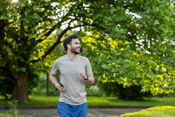 Man jogging in park enjoying morning workout with smartphone and earphones, feeling energized and healthy in nature