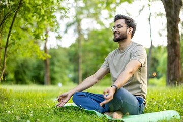 Sportsman practicing yoga meditation in park, enjoying peaceful moment on mat surrounded by nature,...