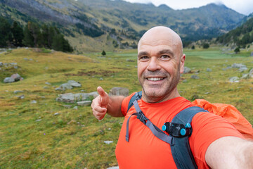 Hiker making thumbs up taking a selfie outdoors.