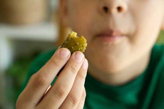 Kid eats cucumber. Focus on the food and face on background