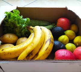 Fresh fruits and vegetables in cardboard box, healthy food. potatoes, lettuce, zucchini, apples, lemons, bananas, avocados at the market. Background, isolated. healthy food.  selective focus