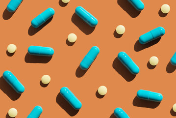 Pattern of blue and yellow pills on orange background. Creative tablets concept