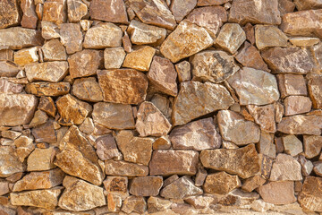 A beautiful texture of an old wall from gray and orange stones with cracks
