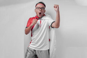 Energetic young Asian man wearing jersey with flag draped over shoulder raising hand in the air.