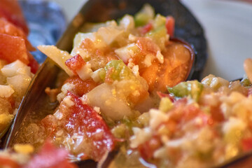 Close-up of a mussel topped with colorful vinaigrette sauce