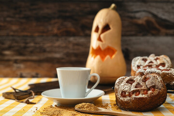 Pumpkin-shaped biscuit with a mug, in the background a Halloween pumpkin, horizontal shot