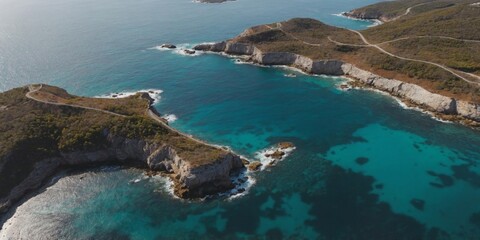 Aerial view of a winding road along a coastal landscape with clear blue waters.