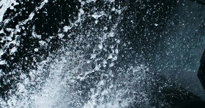 Super slow motion macro of fresh clean pure water cascade stream of old rustic wooden mill is flowing down surrounded by rocks nature at 1000 fps.