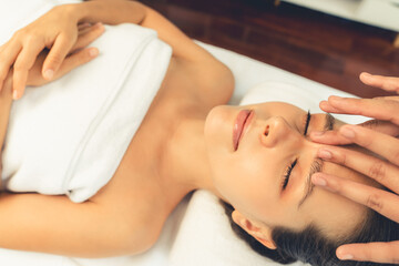Caucasian woman enjoying relaxing anti-stress head massage and pampering facial beauty skin recreation leisure in dayspa modern light ambient at luxury resort or hotel spa salon. Quiescent