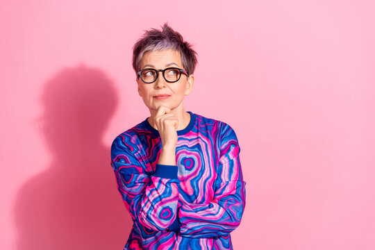 Photo portrait of attractive senior woman thoughtful look empty space dressed blue colorful clothes isolated on pink color background