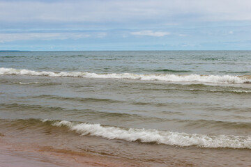 Under a partly cloudly, yet blue sky in late August, Lake MIchigan's waves wash onshore at Harrington Beach State Park, Belgium, Wisconsin