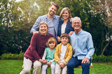 Fototapeta premium Family, generations and outdoor portrait to relax, bench and support in relationship connection. Grandparents, parents and together for security embrace in countryside, vacation and travel to England