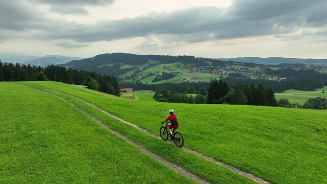 pretty senior woman riding her electric mountain bike on the smooth landscape next to Oberstaufen in the Allgau Alps, Bavaria Germany