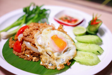 Thai style fried rice with meat, tomatoes, onions, fried egg, fish sauce and various vegetables side dish.