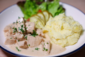 Chicken in cream sauce served with mashed potatoes and salad.