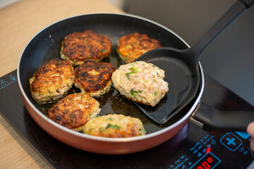 Cooking. The frying pan is on the induction stove, in which meat patties are fried