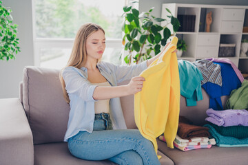 Photo of doubtful sweet lady wear blue shirt doing housework fold clothes indoors room home house