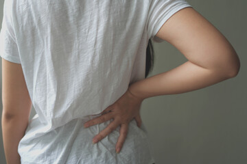 Pain body muscles stiff problem, asian young woman is having the back pain from work hand holding massaging rubbing hurt area, professional and female with problem in health for strain, stress or ache