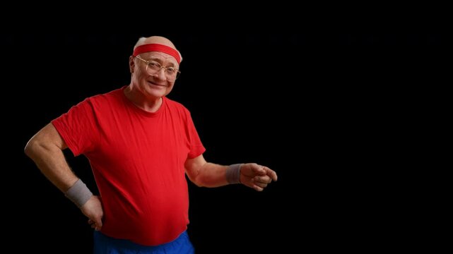 Funny senior athlete pointing to empty space on black background, advertisement