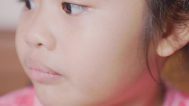 Close-up An attempt to pull out the girl front milk tooth with a thread. A beautiful little girl 6-7 years old has a loose tooth, replacement of permanent teeth, dentistry.